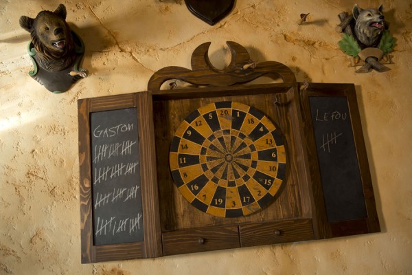 A dart board in a wooden frame and chalkboard for score mounted on an old tavern wall.