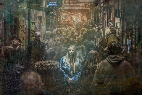 A woman highlighted but alone in a crowd.