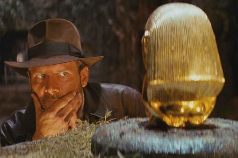 An archeologist abouit to take a gold statue from a pedistal.